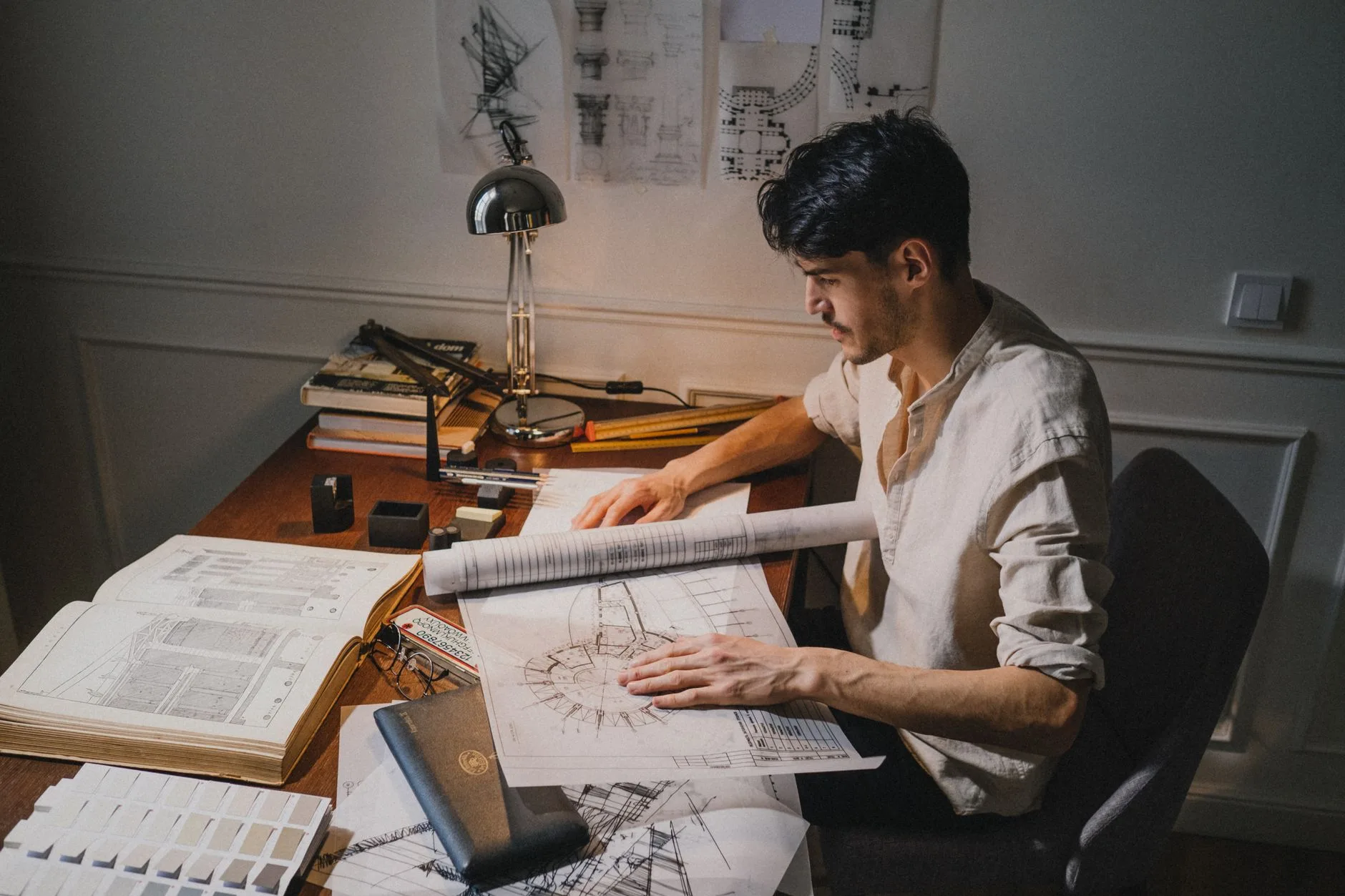 Architecte relisant des plans à son bureau, entre nuancier de couleurs et croquis