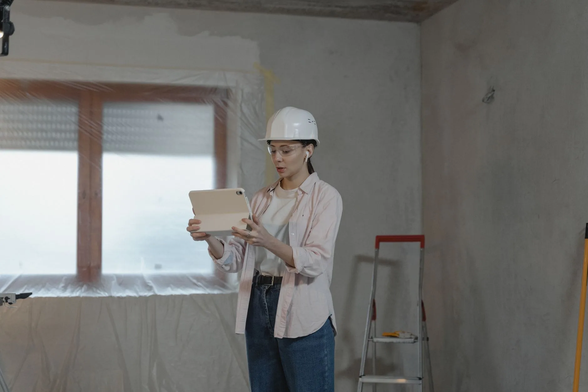Architecte consultant ses plans sur une tablette pendant une visite de chantier